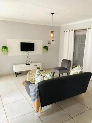a living room with a couch and a tv at Zinathi Lodge in Lebowakgomo