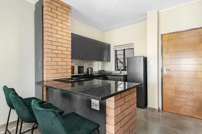 a kitchen with a counter and two green chairs at Smartz Apartment 334 in Midrand