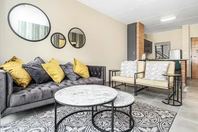 a living room with a couch and a table and mirrors at Smartz Apartment 334 in Midrand