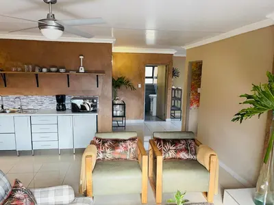 a living room with two chairs and a kitchen at Langalanga on the mountain bend in Tzaneen