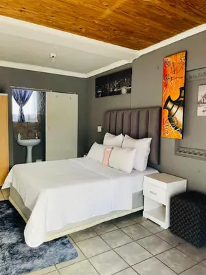 a bedroom with a large white bed and a sink at Mighty7 Guesthouse in Pretoria