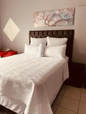a bedroom with a large bed with white sheets at Mighty7 Guesthouse in Pretoria