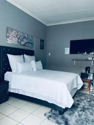a bedroom with a large bed with blue walls at Mighty7 Guesthouse in Pretoria