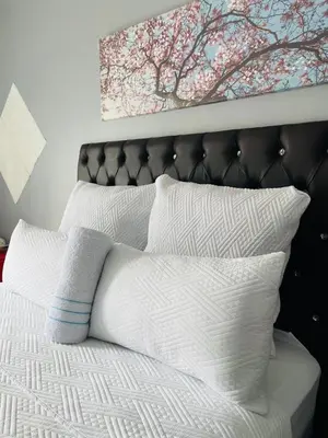 a bed with white pillows and a painting above it at Mighty7 Guesthouse in Pretoria