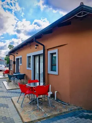 a group of red chairs and a table next to a building at Mighty7 Guesthouse in Pretoria