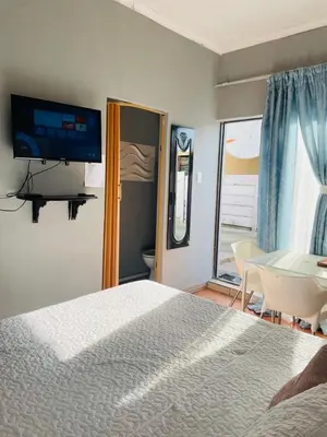a bedroom with a bed and a table and a television at Mighty7 Guesthouse in Pretoria
