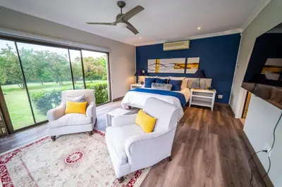 a bedroom with a king sized bed and two chairs at Luxury Boutique Home in Kyalami in Midrand