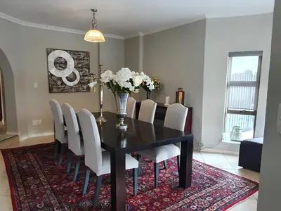 a dining room with a black table and white chairs at Luxury Boutique Home in Kyalami in Midrand