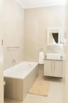 a white bathroom with a tub and a sink at Fumo House Lifestyle Apartments in Midrand