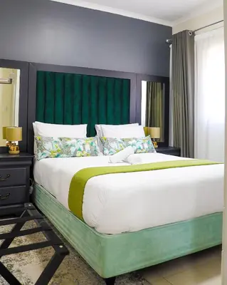 a bedroom with a large bed with a green headboard at Fumo House Lifestyle Apartments in Midrand