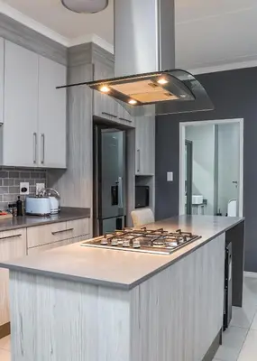 a kitchen with a stove top island in a kitchen at Fumo House Lifestyle Apartments in Midrand