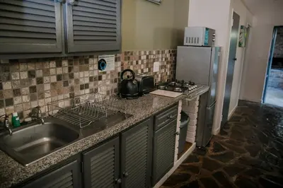 a kitchen with a sink and a stove and a refrigerator at Aan De Vliet Holiday Resort in Hazyview