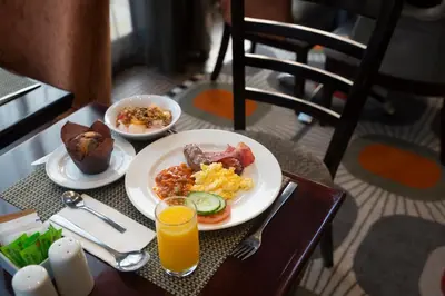 a table with a plate of breakfast food and a glass of orange juice at The RidgePoint Hotel in Witbank