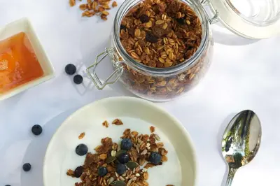 a white plate of granola and a jar of jam at The RidgePoint Hotel in Witbank