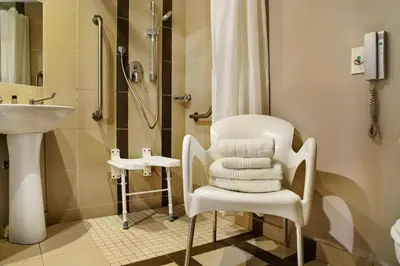 a bathroom with a white chair and a shower at The RidgePoint Hotel in Witbank
