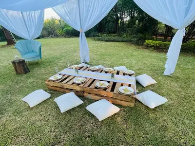 a table with white pillows on the grass with curtains at The Bliss Boutique in Louis Trichardt