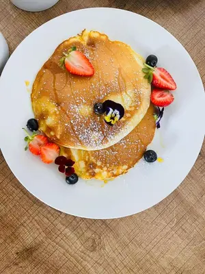 a white plate with pancakes with strawberries and berries at The Bliss Boutique in Louis Trichardt