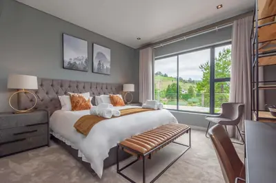 a bedroom with a large bed and a large window at Misty Meadows in Dullstroom