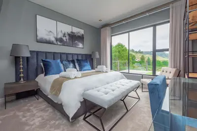 a bedroom with a large bed and a large window at Misty Meadows in Dullstroom