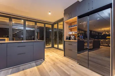 a kitchen with gray cabinets and a wooden floor at Misty Meadows in Dullstroom