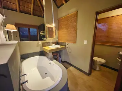 a bathroom with a tub and a toilet and a sink at 10 Raptors Lodge in Hoedspruit