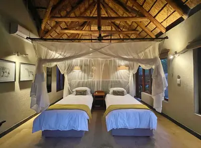 two beds in a bedroom with a canopy at 10 Raptors Lodge in Hoedspruit