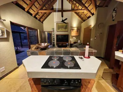 a kitchen with a stove and a living room at 10 Raptors Lodge in Hoedspruit