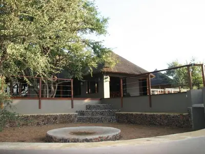 a building with a tree and a stone bench in front of it at Mount Marula Game Lodge - Tambotie in Kwarriekraal
