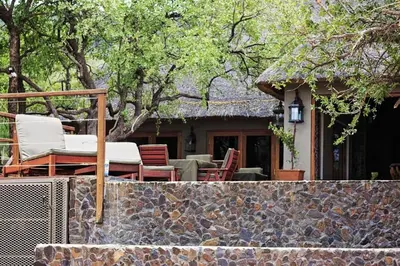 a house with a patio with chairs and a stone wall at Mount Marula Game Lodge - Tambotie in Kwarriekraal