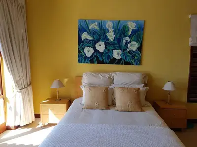 a bedroom with a white bed with a painting on the wall at Pecanwood Home Away from Home in Hartbeespoort