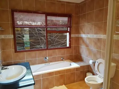 a bathroom with a tub and a toilet and a sink at Pecanwood Home Away from Home in Hartbeespoort