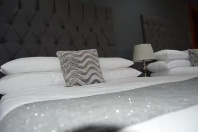 a bedroom with two beds with white pillows and a headboard at Honolulu Lifestyle Guest Lodge in Burgersfort