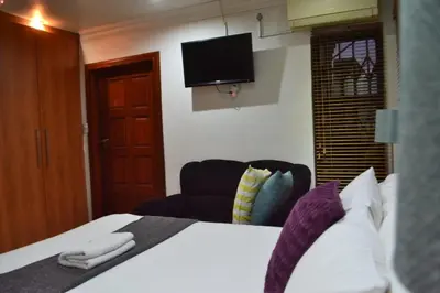 a hotel room with a bed and a flat screen tv at Honolulu Lifestyle Guest Lodge in Burgersfort
