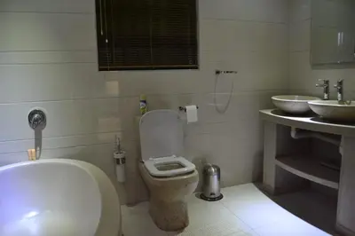 a bathroom with a toilet and two sinks at Honolulu Lifestyle Guest Lodge in Burgersfort