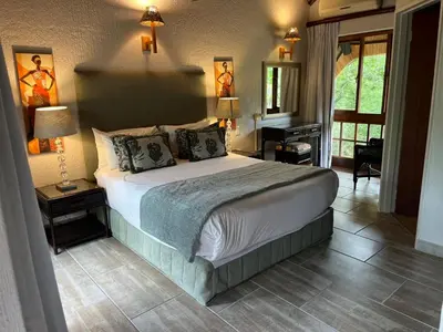 a bedroom with a bed and a desk and a piano at Dreamy 3 bedroom villa on the edge of the Sabie River in Kruger Park Lodge in Hazyview