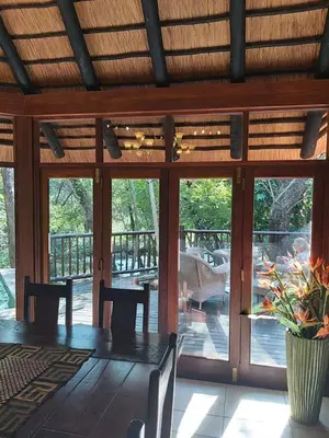 a dining room with a table and chairs and sliding glass doors at Dreamy 3 bedroom villa on the edge of the Sabie River in Kruger Park Lodge in Hazyview