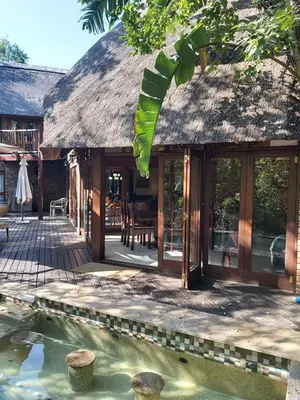 a house with a thatched roof and a swimming pool at Dreamy 3 bedroom villa on the edge of the Sabie River in Kruger Park Lodge in Hazyview