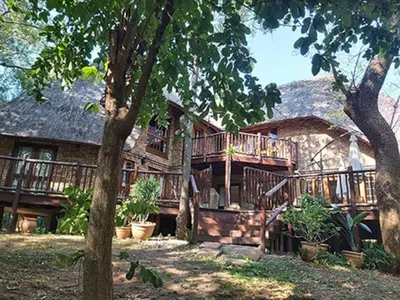 a large wooden house with a large deck at Dreamy 3 bedroom villa on the edge of the Sabie River in Kruger Park Lodge in Hazyview