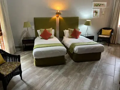 a hotel room with two beds and a chair at Dreamy 3 bedroom villa on the edge of the Sabie River in Kruger Park Lodge in Hazyview