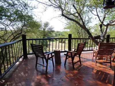 three chairs and a table on a deck with a fence at Zazu Private Bush Lodge, Formerly Masodini in Hoedspruit