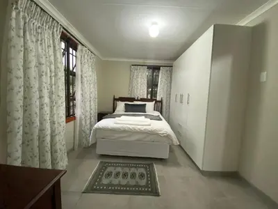 a bedroom with a bed and a large window at Man and Dog Log Cabin in Midrand