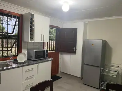 a kitchen with a refrigerator and a microwave at Man and Dog Log Cabin in Midrand
