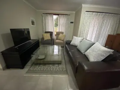 a living room with a leather couch and a piano at Man and Dog Log Cabin in Midrand