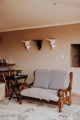 a living room with a couch and horns on the wall at Sorgenfri in Hendrina