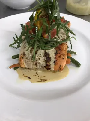 a white plate with a fish dish with greens on it at Sasavona Boutique Hotel in Polokwane