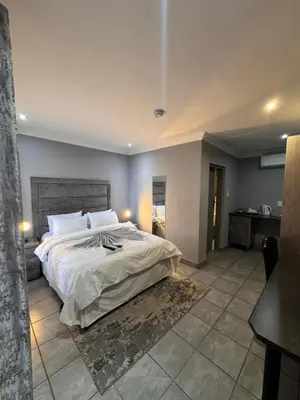 a bedroom with a large bed in a room at President Guest Lodge in Louis Trichardt