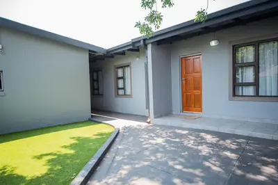 a white house with a brown door and a yard at President Guest Lodge in Louis Trichardt