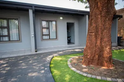 a tree in the grass next to a house at President Guest Lodge in Louis Trichardt
