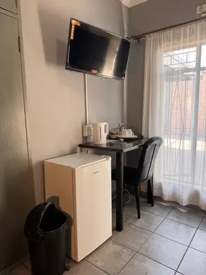 a kitchen with a desk and a table with a television at President Guest Lodge in Louis Trichardt
