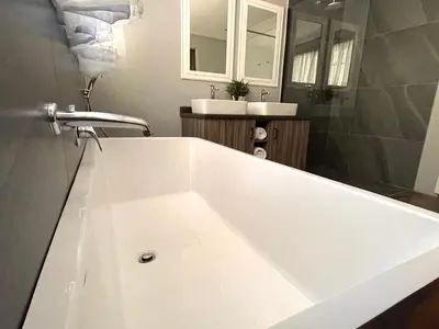 a white tub in a bathroom with two sinks at The Lion Mansion - on Solar live and work anywhere in Pretoria
